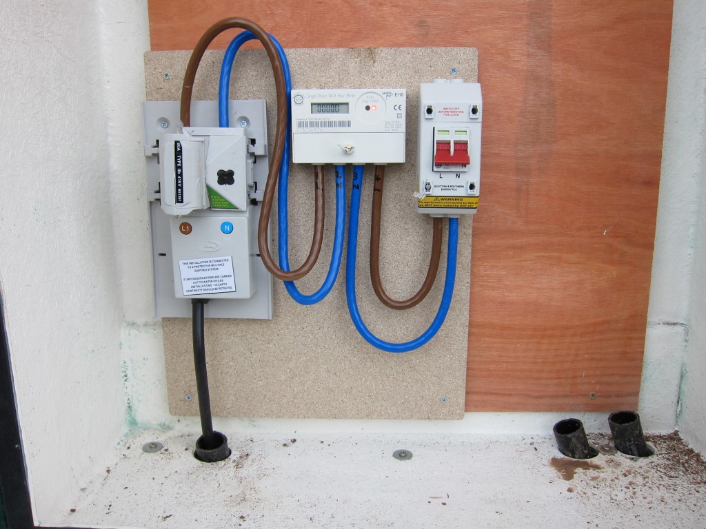 Newly-installed cutout (Western Power Distribution, left), meter and isolator (Southern Electric, centre and right) in GRP enclosure.