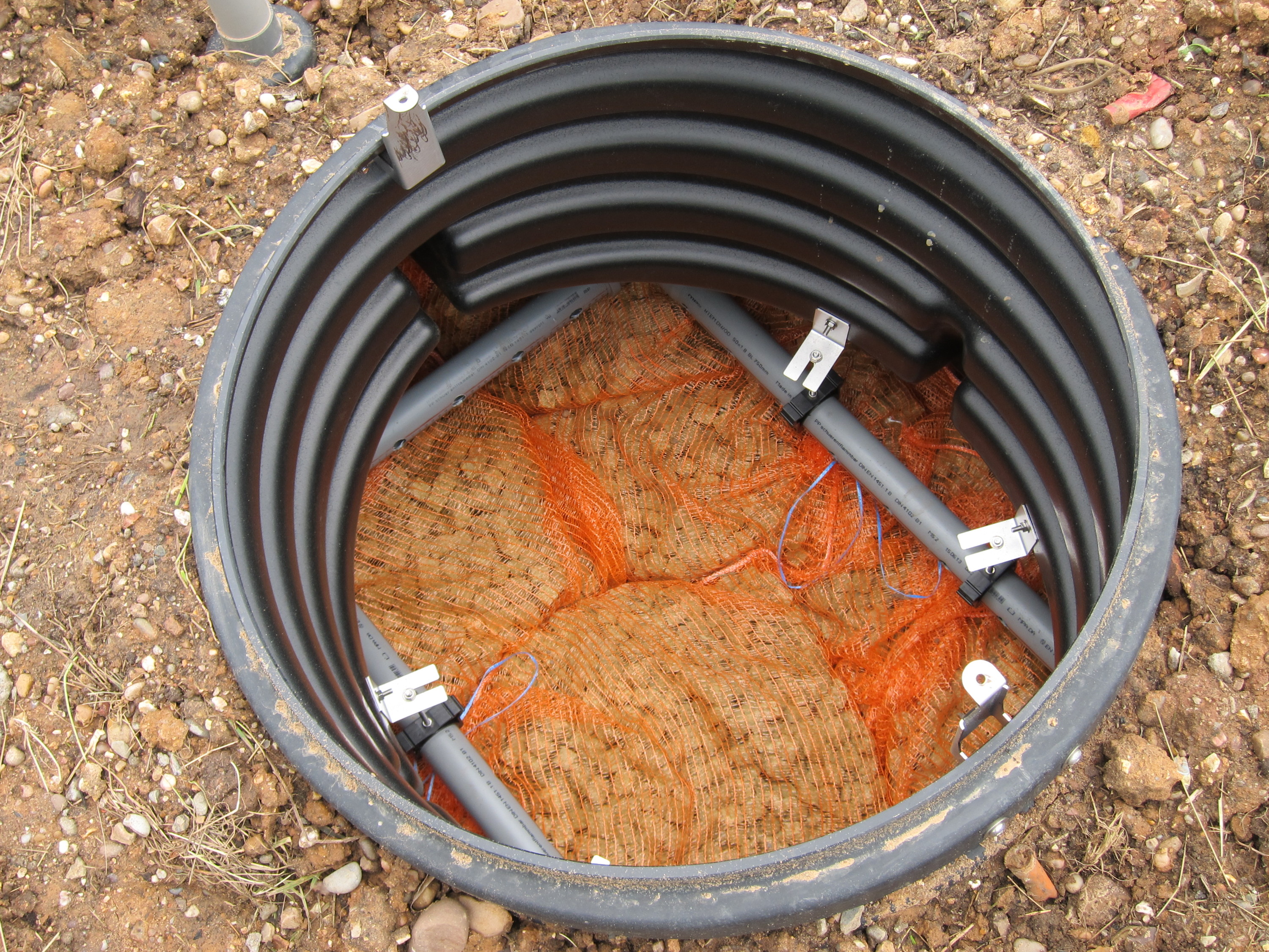 The view in the top of the Biorock unit, showing the grey delivery pipes and the foam media inside orange string bags
