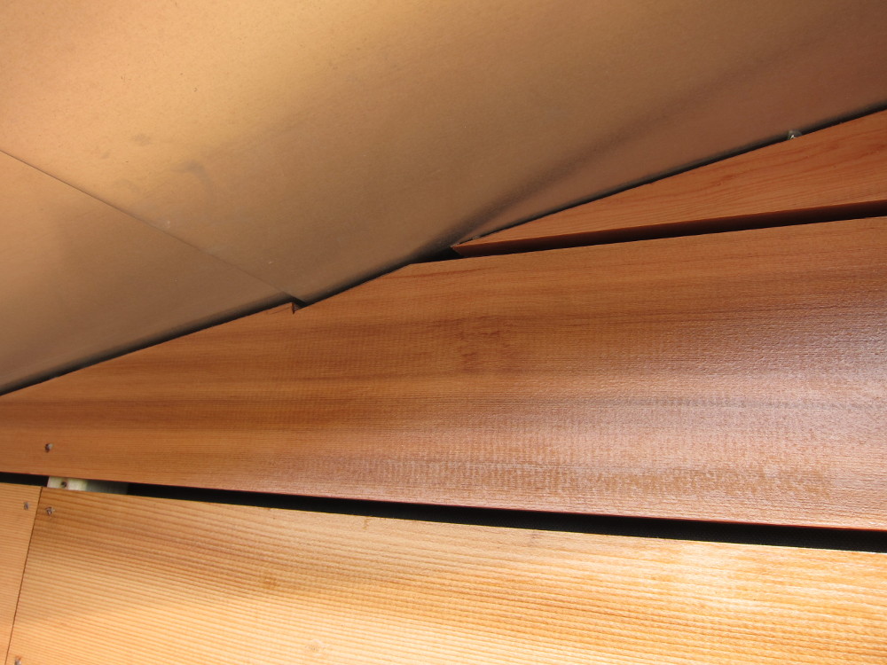 Cedar cladding boards carefully cut around zinc roof covering