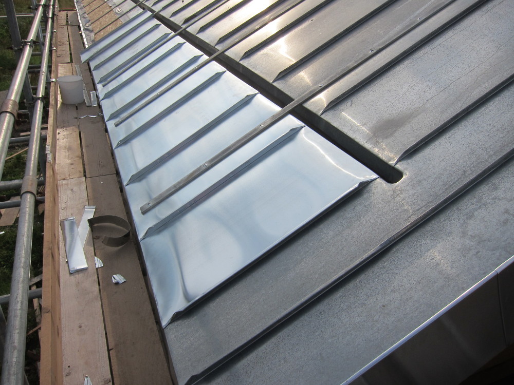 Installing the zinc below the concealed gutter on the south roof - very obvious difference in weathering after only a few days